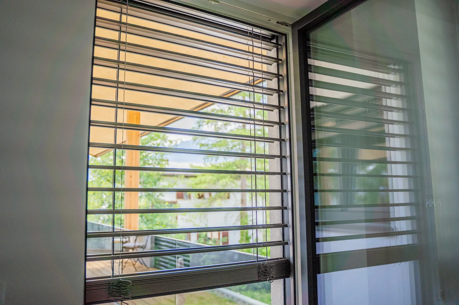 Raffstore vor einem Fenster, Blick auf eine überdachte Terrasse