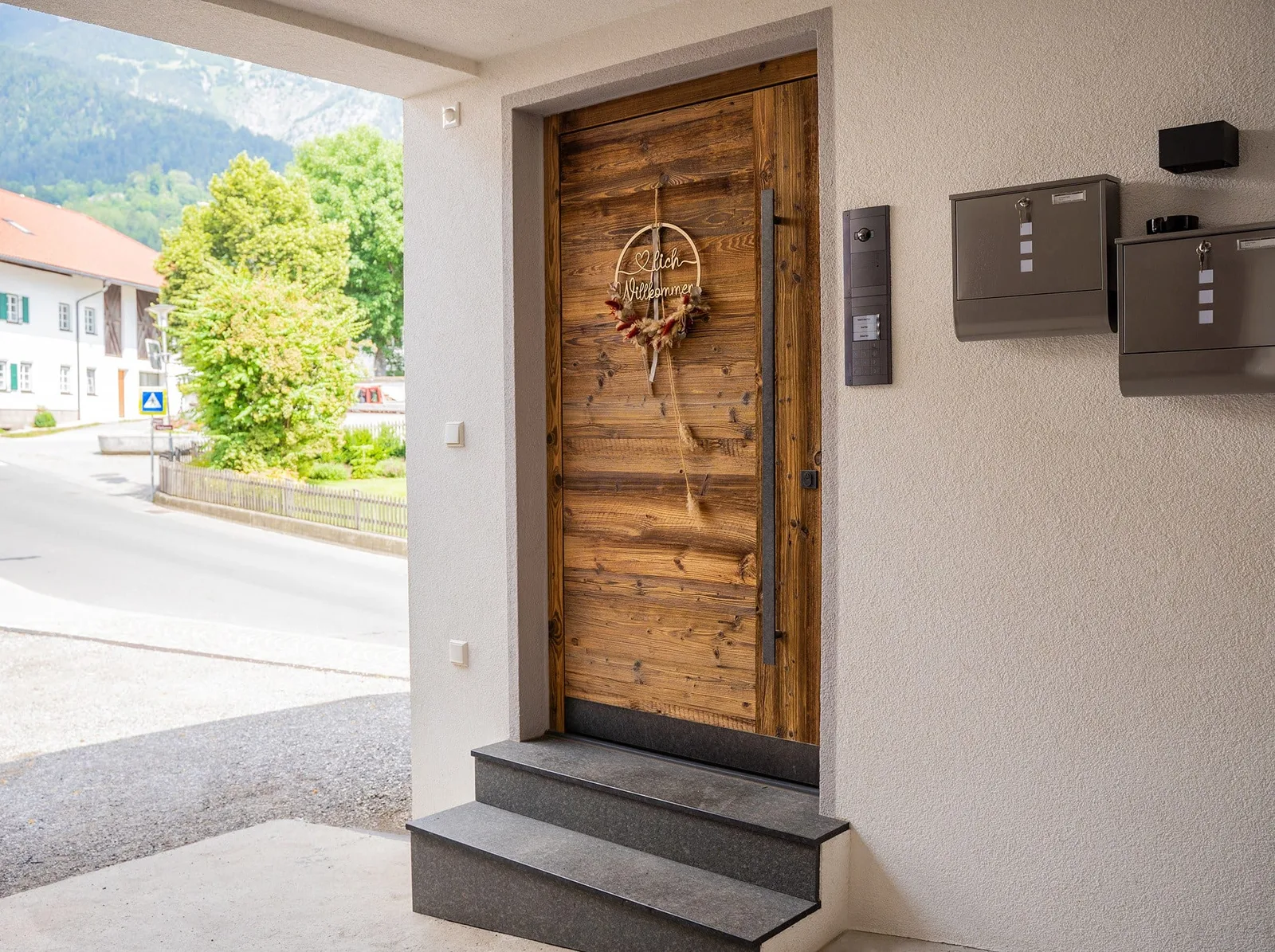 Haustür aus Altholz mit Willkommenskranz und Steinstufen