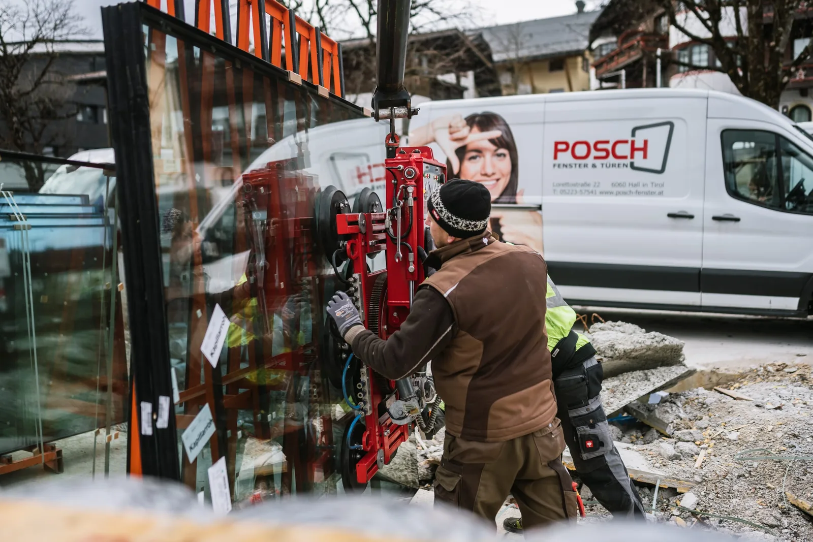 Monteure setzen mit einem Glassauger eine große Scheibe, dahinter der POSCH-Firmenbus