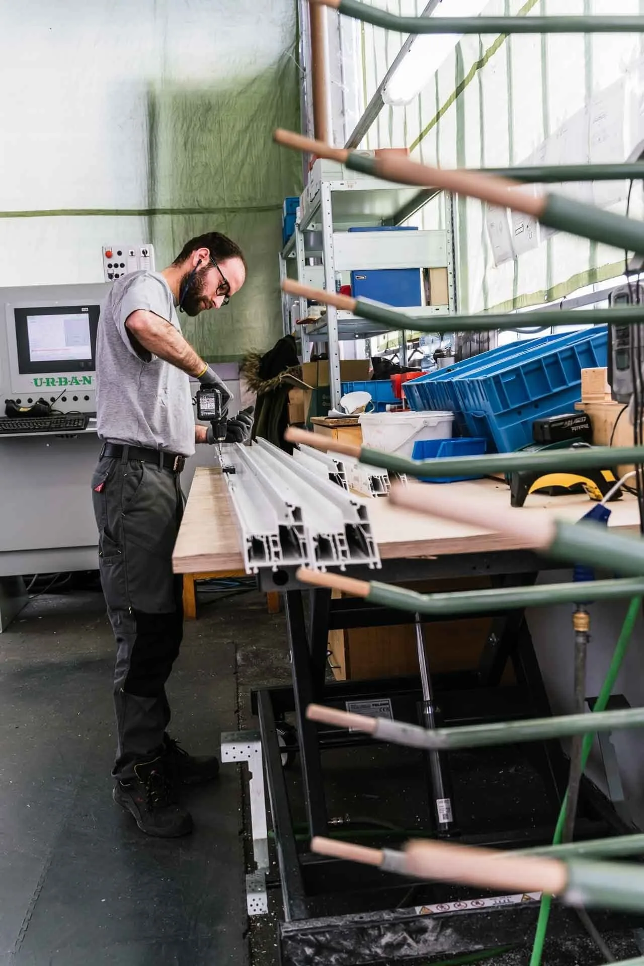 Mitarbeiter an der Werkbank mit Kunststoffprofilen, dahinter eine Maschine