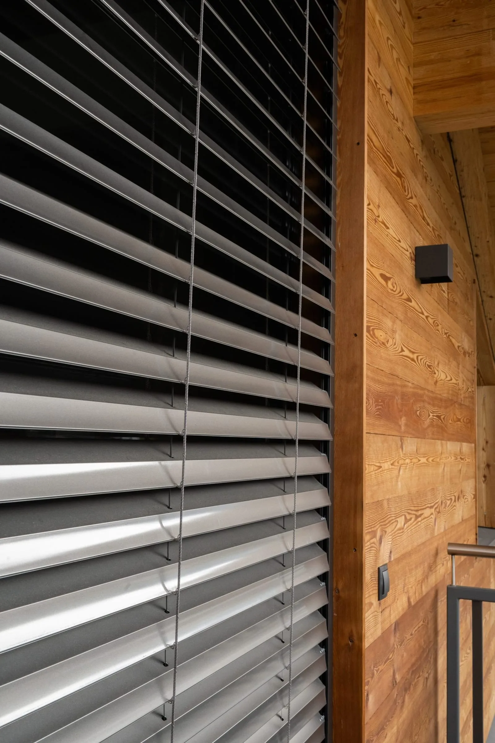 Raffstore-Lamellen neben einer Holzfassade