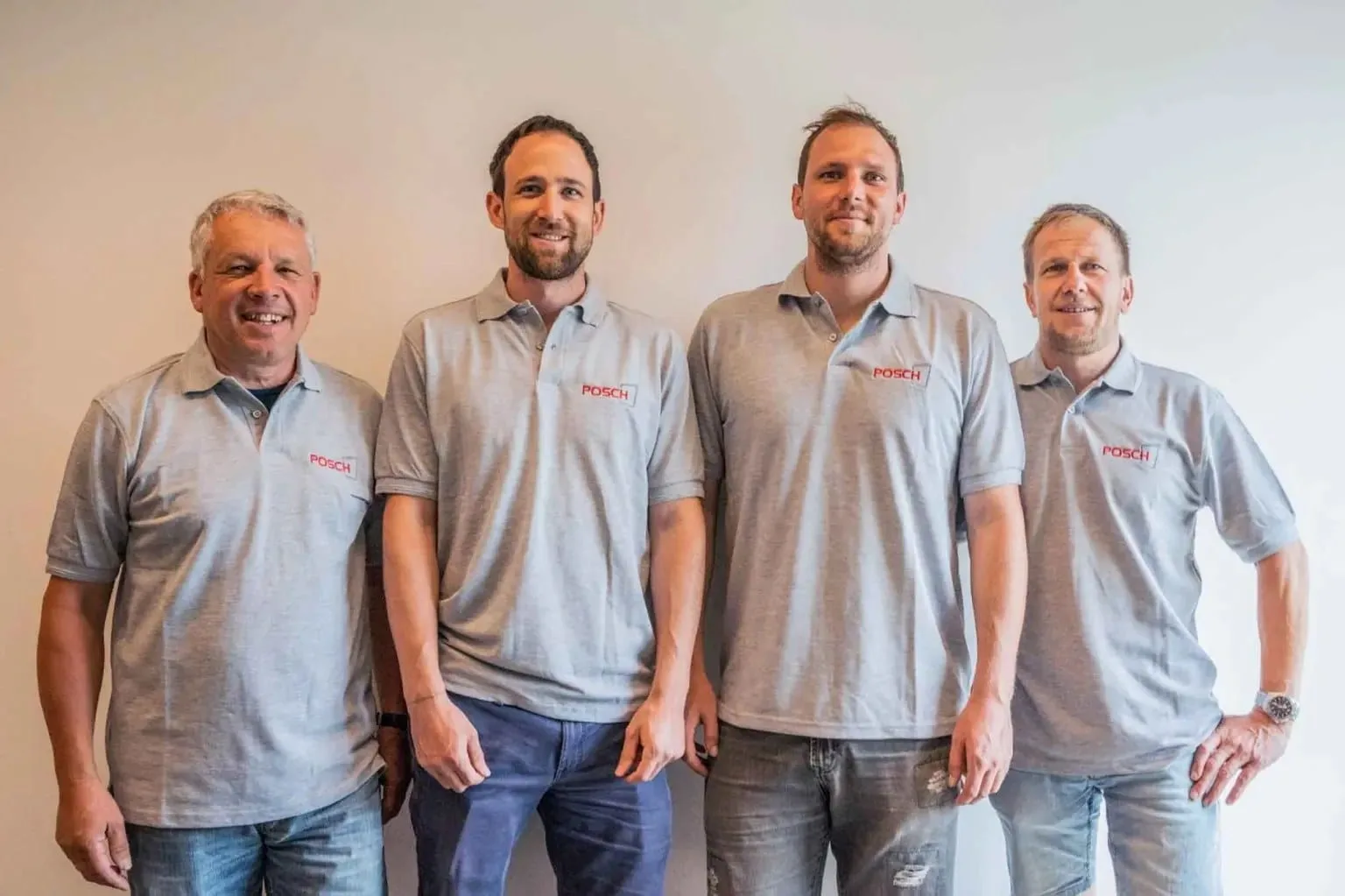 Vier Mitarbeiter in grauen POSCH-Poloshirts