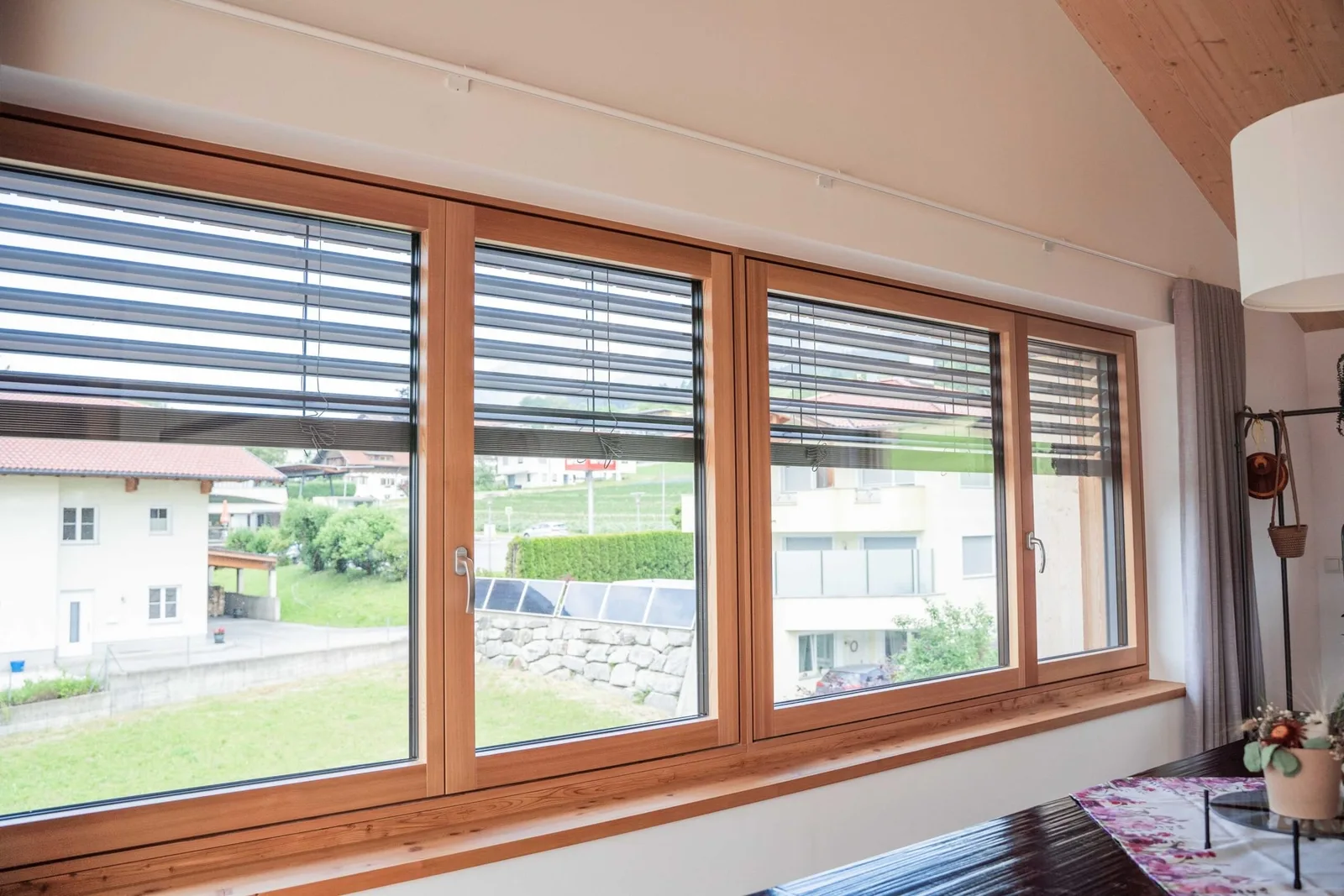 Wohnraum mit dreiteiligem Holz-Alu-Fenster und Raffstore