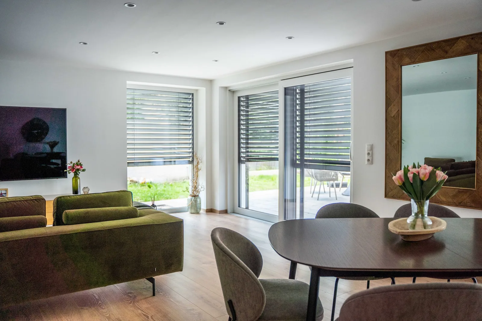 Wohnzimmer mit Raffstores und großer Schiebetür zur Terrasse